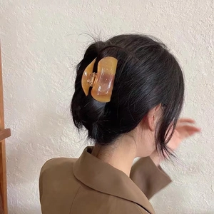 Detail view of large amber acetate hair claw clip with marble texture for updo hairstyles