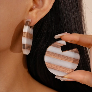 Retro C-shaped earrings with white resin and brown wood grain stripes on a female model