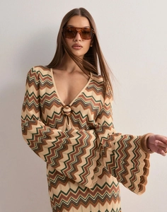 Dettaglio dello scollo a V con anello in resina e maglia a zig-zag colorata sull'abito lungo
