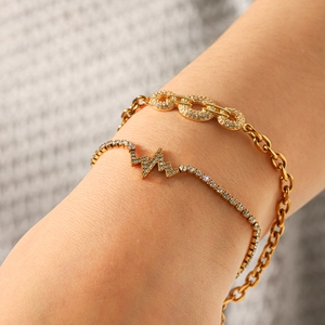 Detail of layered gold stainless steel bracelets with pave zircon heart rhythm pendant