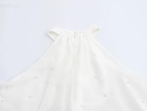 Detailaufnahme des Neckholder-Ausschnitts mit Perlenknöpfen am weißen Netzkleid