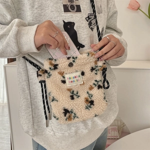 Detail of plush floral crossbody bag showing soft texture and woven strap on model