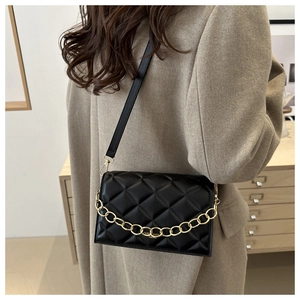 Detail of black quilted shoulder bag with gold chain strap and metallic buckle