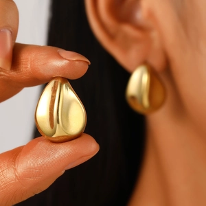 Detailed close-up of polished gold teardrop earrings with a smooth mirror finish