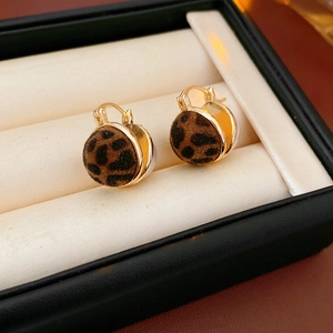Close-up of leopard print hoop earrings in a black jewelry box with beige lining