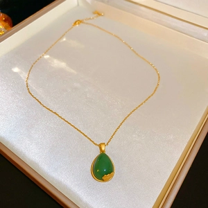 Close-up of teardrop green glazed zircon earrings with gold plated hooks and leaf details