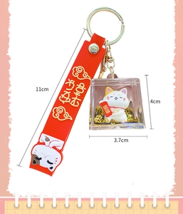 Detail of lucky cat keychain featuring red silicone strap and gold glitter liquid charm