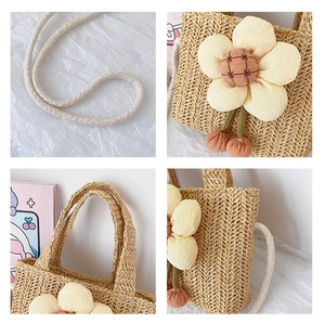 Detail view of beige straw bag showing cotton rope strap and large floral decoration