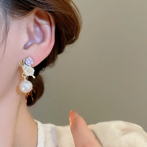 Gros plan d'élégantes boucles d'oreilles lavande avec pétales en émail et perles