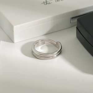Détail d'une bague ouverte géométrique argentée double couche sur écrin minimaliste