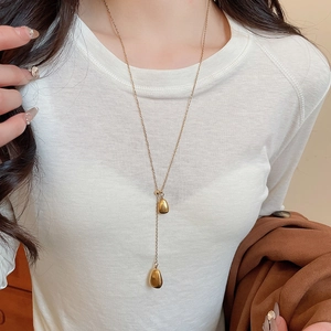 Close-up of 18k gold plated double teardrop pendant necklace on white clothing