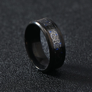 Macro shot of black stainless steel ring with blue carbon fiber and silver dragon pattern