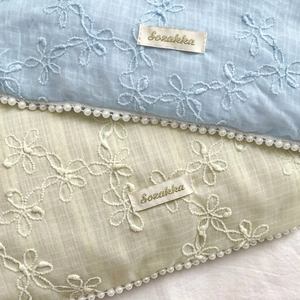 Nahaufnahme von Blumenstickerei auf pastellfarbenem Chiffon mit Perlenkante