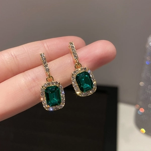 Macro shot of rectangular emerald green stone earrings with crystal pavé and gold finish