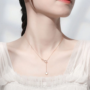 Close-up of rose gold infinity heart necklace with crystal accents on a model's neck