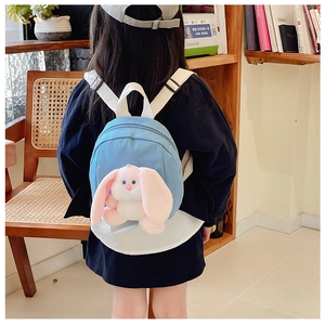 Toddler wearing a light blue canvas backpack featuring a pink plush long-eared bunny toy