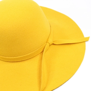 Detailed close-up of a vibrant yellow wool fedora hat with a delicate matching bow