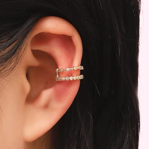 Detail macro view of a double-layered gold-tone ear cuff with inlaid clear rhinestones