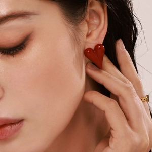 Minimalist red heart stud earrings with gold plating shown on a model side profile