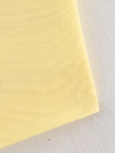 Macro shot of yellow linen blend fabric showing detailed breathable weave texture