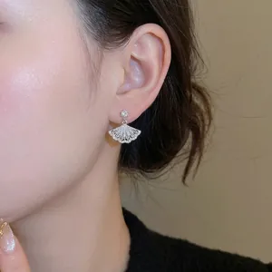 Elegant silver fan-shaped earrings with sparkling white zircons worn on ear for women