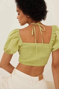 Detail of green puff sleeve open back top with ties and ruched texture back view