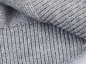 Close-up of grey knit vest fabric showing detailed rib-knit texture and soft wool blend