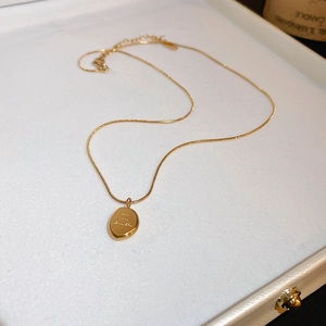 Détail d'un collier avec pendentif ovale doré dans un écrin à bijoux blanc