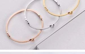 Macro view of gold silver and rose gold heart bracelets with crystal pavé on white stone