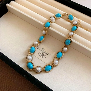 Close-up of vintage gold necklace with turquoise stones and pearls in a velvet jewelry box