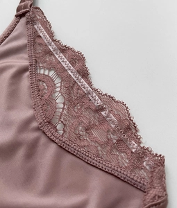 Detailed macro view of sheer lace trim and smooth silk fabric on pink lingerie