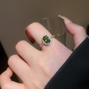 Close-up of 18k gold plated ring with green oval gemstone and pavé diamonds on finger