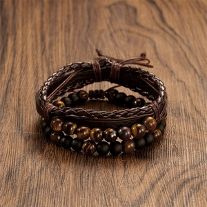 Detail of layered leather bracelet set with tiger eye and matte agate beads on wood