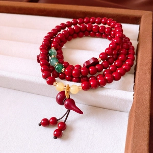 Detail of red cinnabar beaded bracelet with gourd pendant in a classic jewelry box