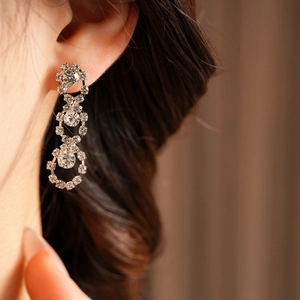 Close-up of sparkling silver tassel earrings with round geometric rhinestones on ear