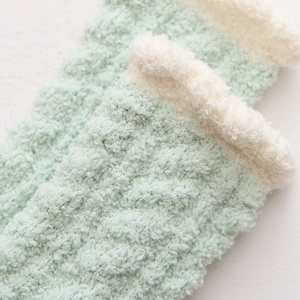 Close-up of thick mint green coral fleece socks with soft white plush trim for warmth