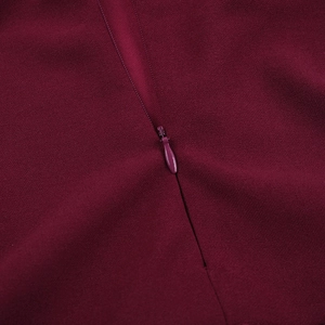 Détail de la fermeture éclair invisible sur la robe tissée de couleur bordeaux