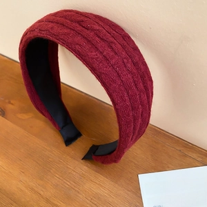 Détail d'un serre-tête tricoté bordeaux épais avec texture sur fond en bois