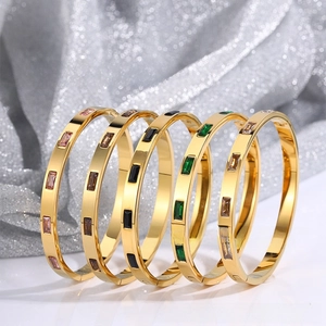 Detailed view of stacked gold titanium bracelets featuring vibrant rectangular zircons