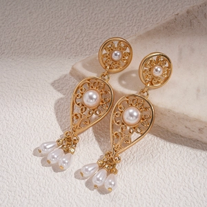 Detail of vintage gold pearl earrings with floral cutout and elegant teardrop tassel