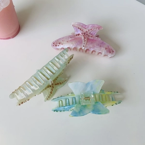 Close-up of large acetate starfish hair claws with sparkling rhinestones in multiple colors