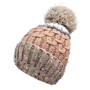 Détail du bonnet en maille épaisse avec pompon bicolore et motifs tissés aux tons terre