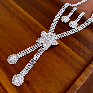 Detailed view of silver rhinestone jewelry set with star tassel on dark wood