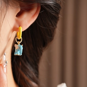 Close-up of cute blue elephant earring with pink ears and golden ring on a model