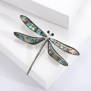 Vintage silver dragonfly brooch featuring natural abalone shell wings and emerald accents