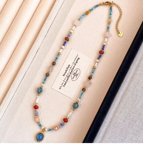 Détail du collier de perles bohème avec pendentif bleu cerclé d'or et fermoir en acier