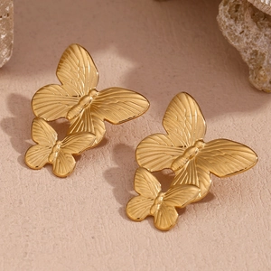 Macro shot of 18K gold plated stainless steel butterfly earrings on a natural stone base