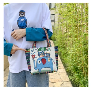 Detailed close-up of ethnic embroidered handbag featuring colorful owl and elephant patterns