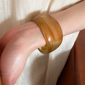 Detail of amber resin wide bangle showing unique translucent sand-like texture on wrist