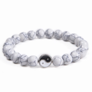 Detailed macro view of white turquoise beads with a silver Yin Yang Tai Chi charm bracelet